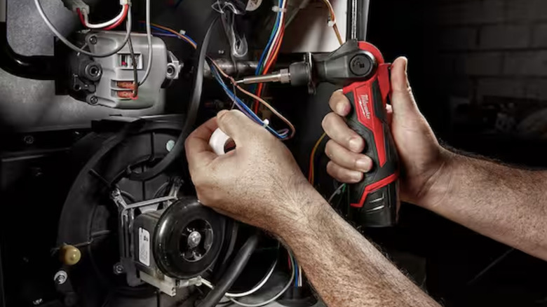 A person using a Milwaukee soldering iron to connect wires