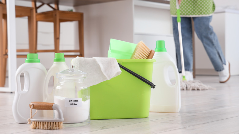 natural floor cleaning products including baking soda on the floor with person mopping in background