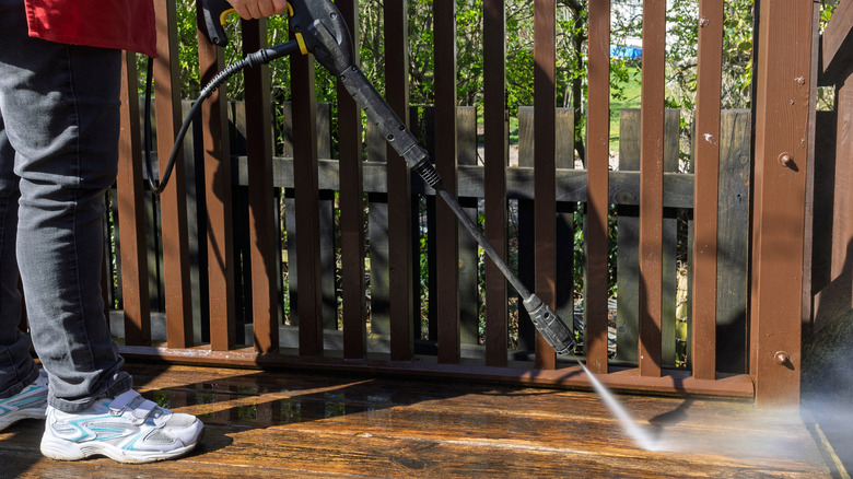 Person using a pressure washer to clean their deck