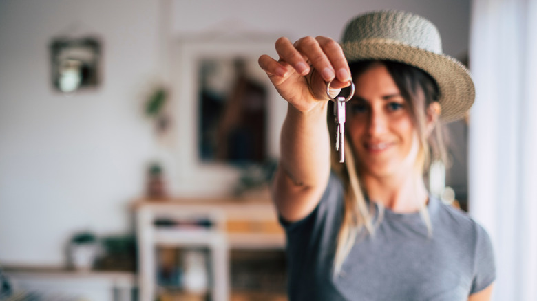 woman in hat holding key