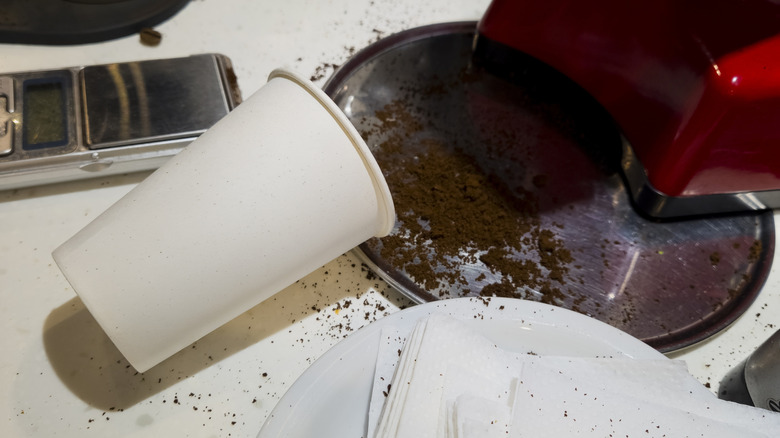 Tipped over paper cup spilling coffee grounds on counter