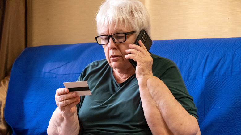 A senior woman holding a card and speaking on phone