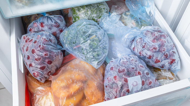A thin layer of ice on bagged veggies inside a drawer in a fridge