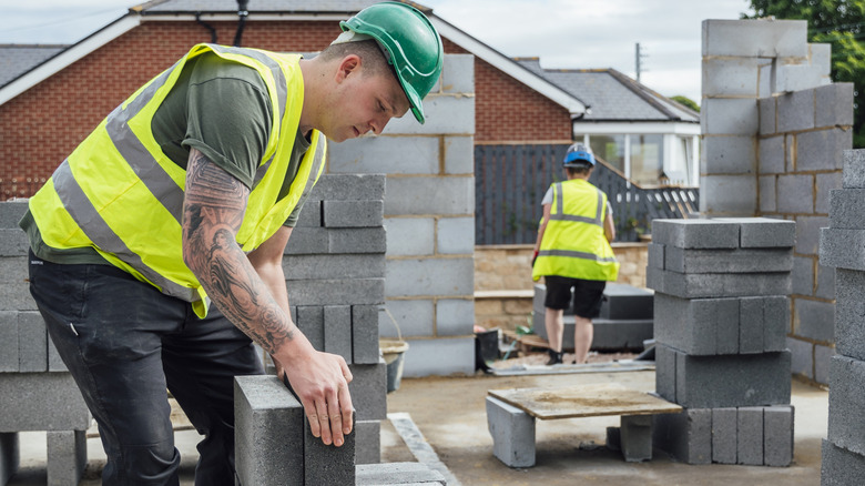 Construction worker stacking concrete blocks for a newly built structure.