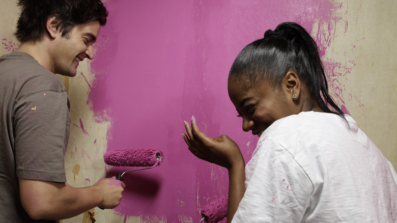 people painting hot pink wall