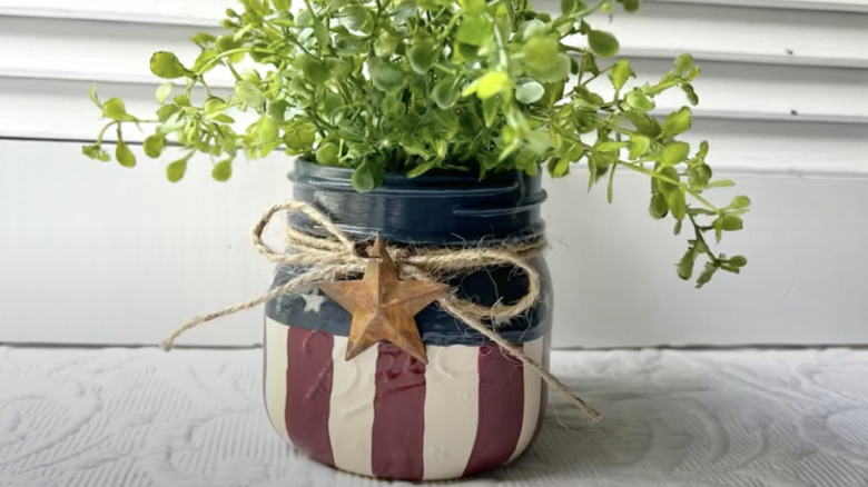 A decorated mason jar with a plant growing in it