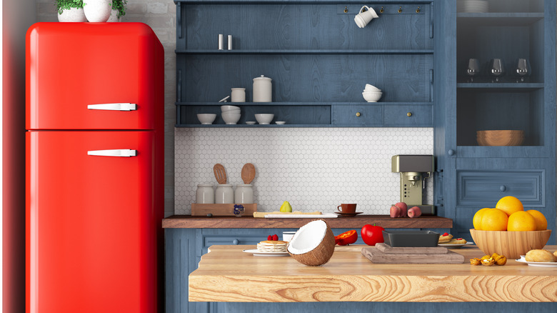 A red refrigerator is displayed in a 1950s style retro kitchen scene