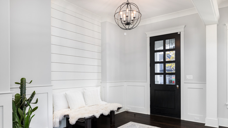 White foyer with dark door