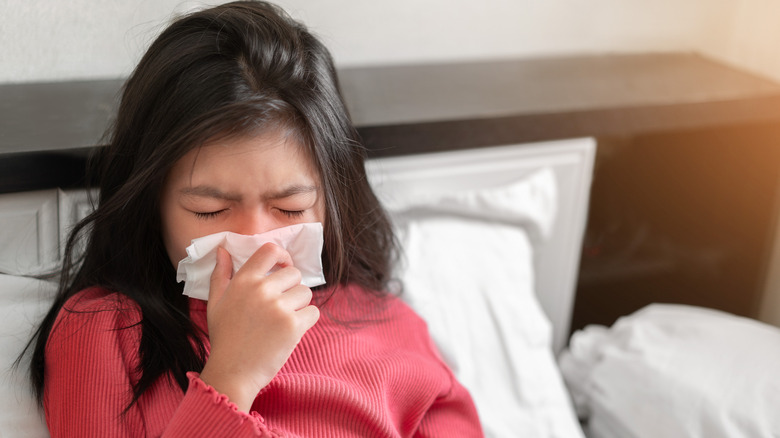 child sneezing into tissue