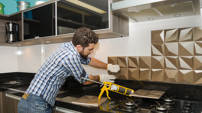 person installing kitchen backsplash 