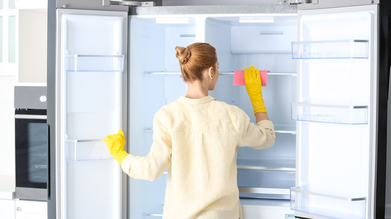 Person wiping down fridge inside