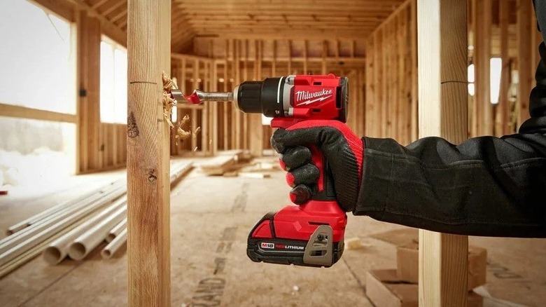Person using a 1/2-inch Milwaukee impact driver on wood framing