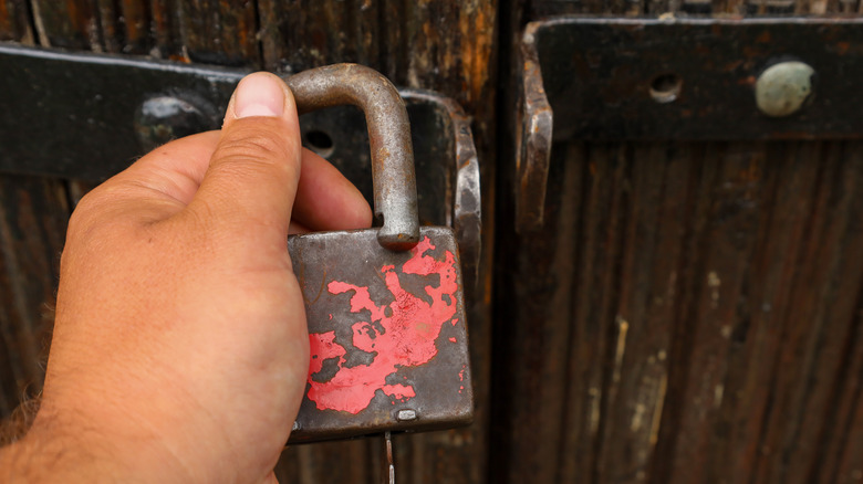 Person opening a lock on a backyard shed