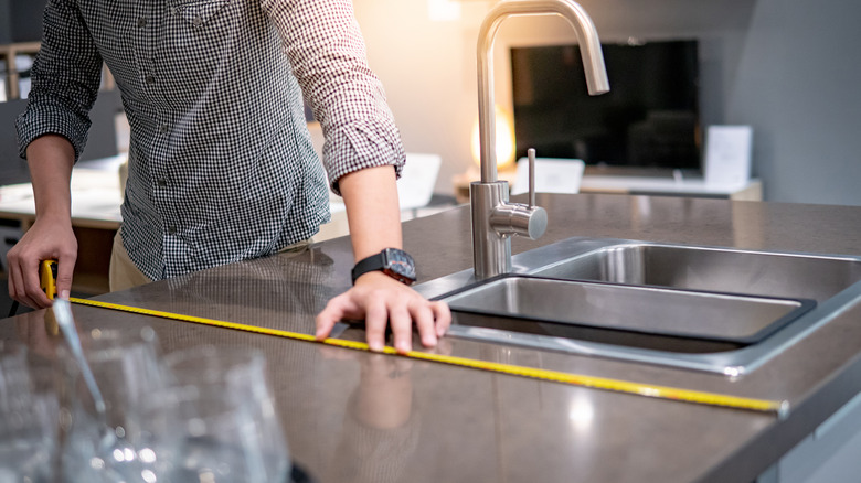 person measuring countertop