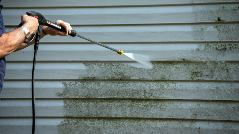 Man power washing house