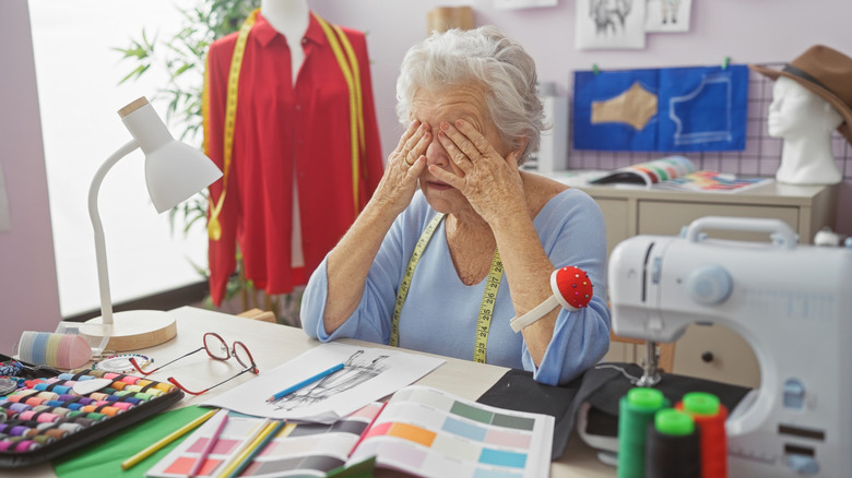 An older woman with clutter all over her sewing room
