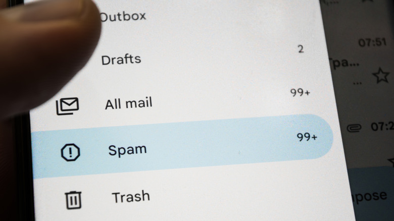 A person's phone screen with their thumb on top in an email app