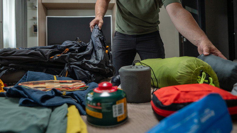 A person packing up all of their camping gear into a bag