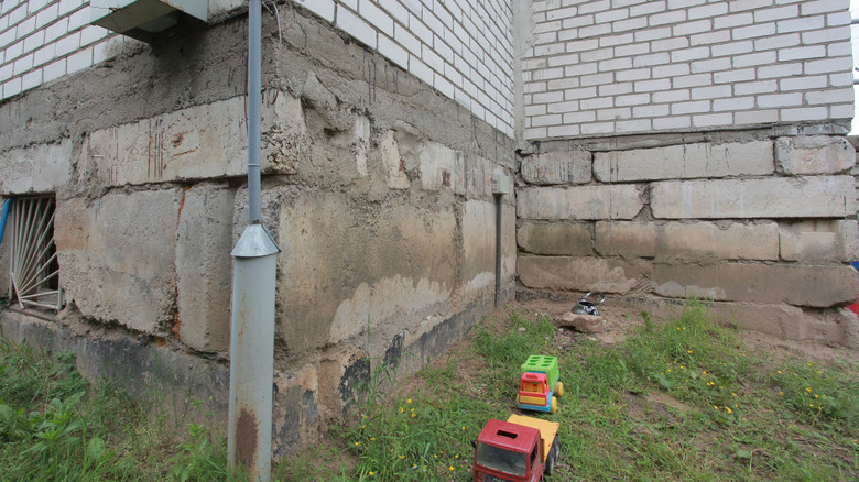 Dry soil around a house's foundation with toys lying around