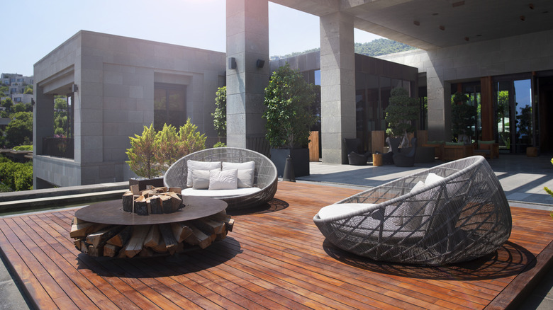 An exposed wood deck with two love seats and a fire pit