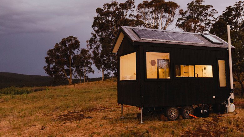 black tiny house in a field