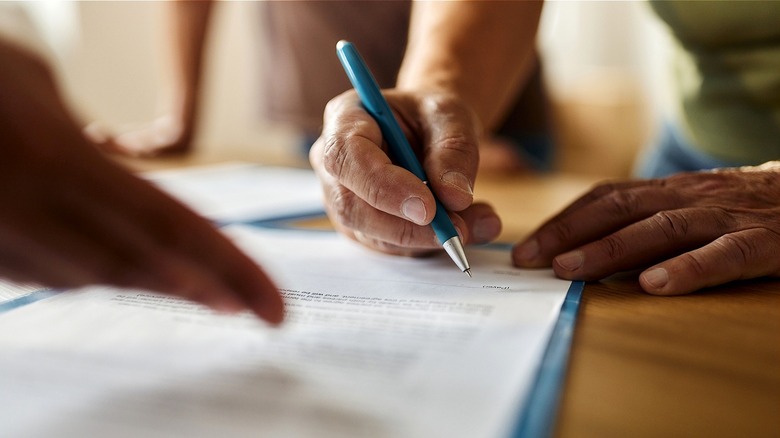Close-up of a person signing a document with a blue pen
