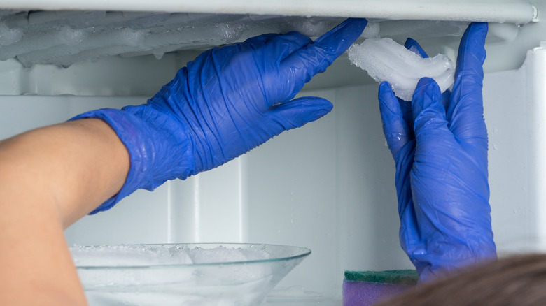 Gloved hand defrosting freezer