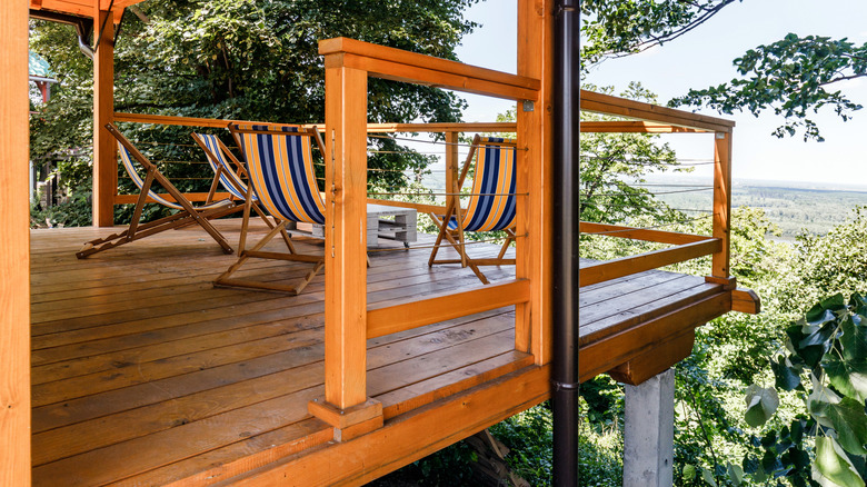 Balcony with deck chairs and table among greenery.