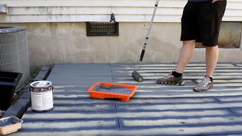 Person using roller to paint deck made of pallet wood
