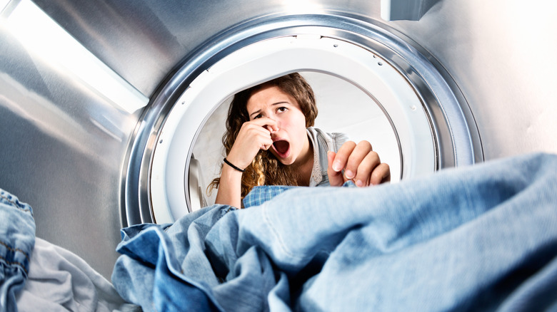 woman doing laundry and holding nose