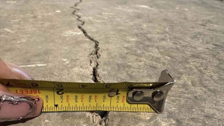 A concrete crack being measured with measuring tape
