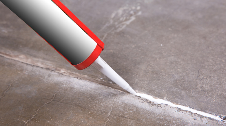 A red and white caulk gun applying concrete caulk
