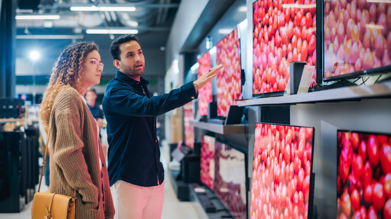 A salesman showing a woman TVs in a store