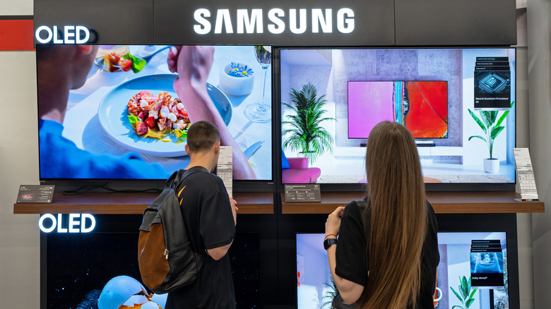 Two people looking at a display of Samsung TVs in a store