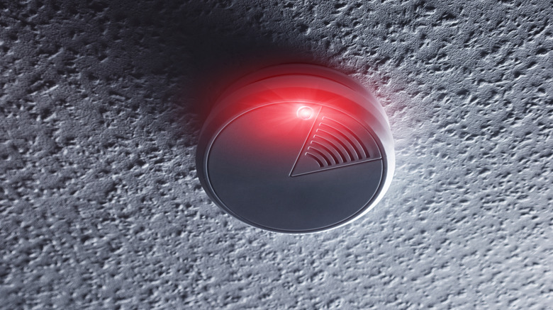 Dark room with red light flashing on smoke alarm.