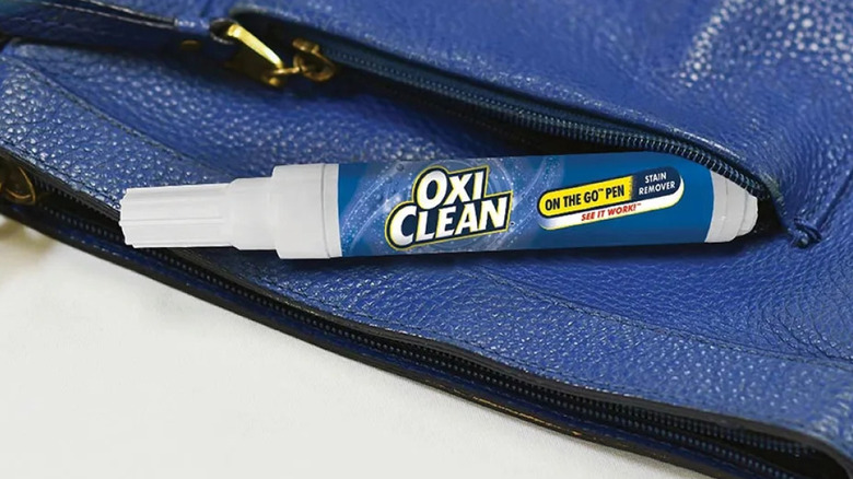 Mini OxiClean stain remover on-the-go pen sticking out of blue pleather purse pocket