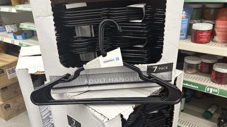 Black plastic clothing hangers on stack of boxed hangers in messy dollar store aisle