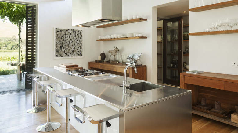 Stainless steel island in modern kitchen with steel bar stools