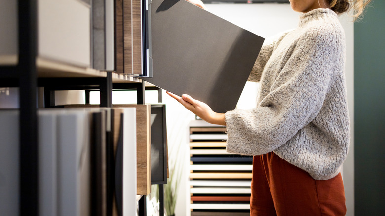 Person lifting countertop sample onto shelf in showroom