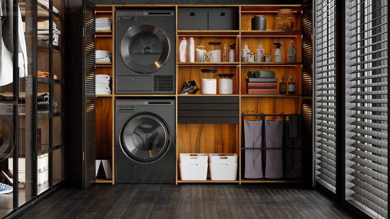 A modern laundry room with warm, moody, dark-wood flooring