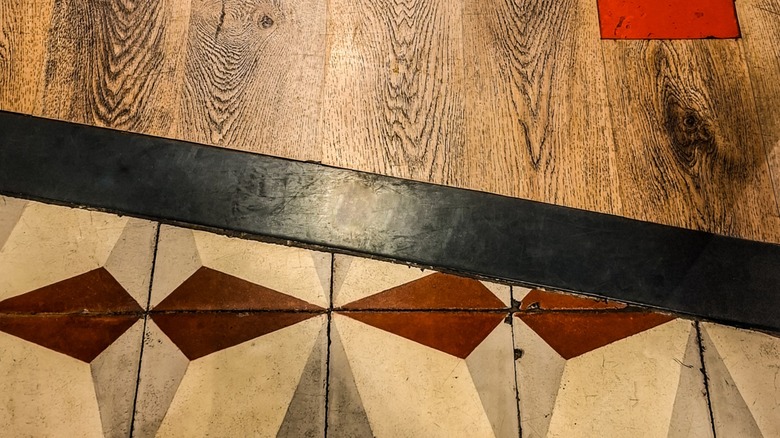 Close-up of a mixed-material floor, with wood planks and stone-inlay tiles
