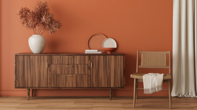 An earthy home scene with terracotta-colored walls and warm wood flooring
