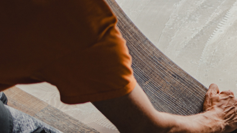 A worker installing planks of vinyl flooring