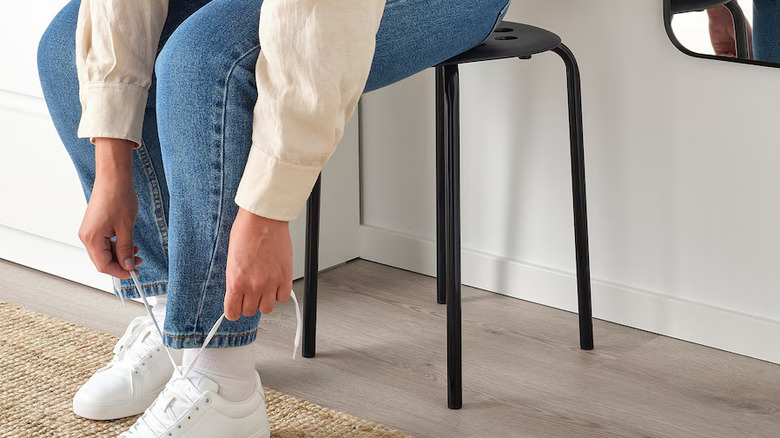 A person tying their shoe on IKEA's MARIUS stool