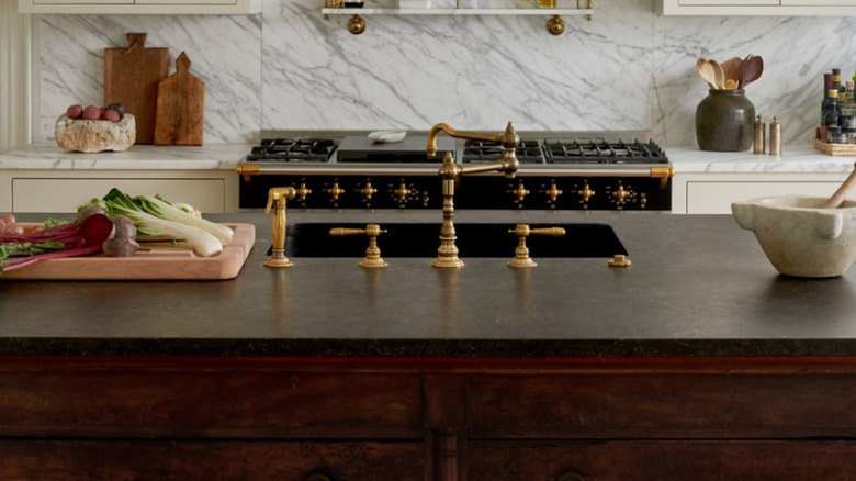 Brass sink fixtures against a dark marble countertop.