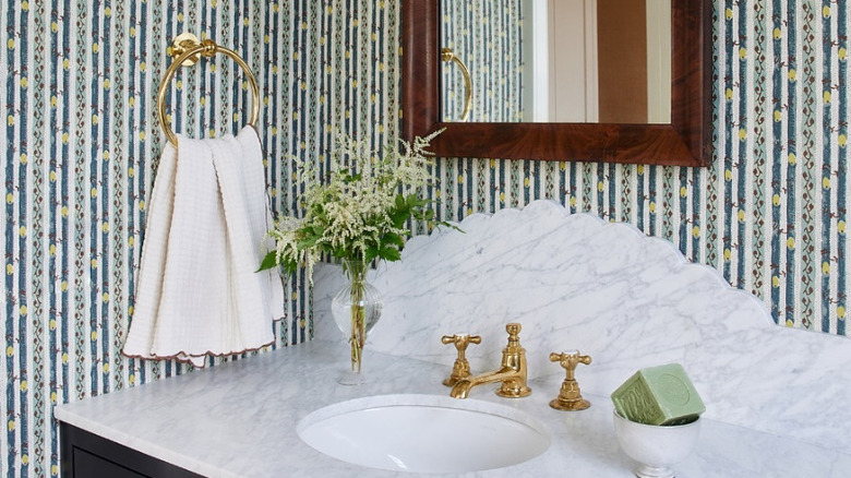 Brass sink and towel holder in a bathroom with wallpaper