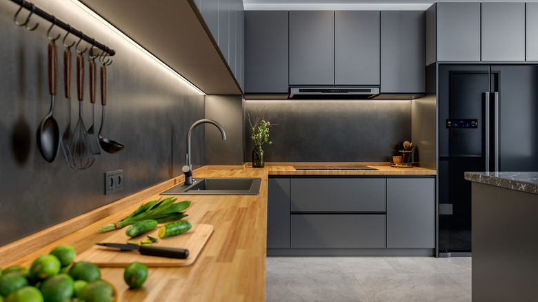 An all black kitchen with butcher block countertops.