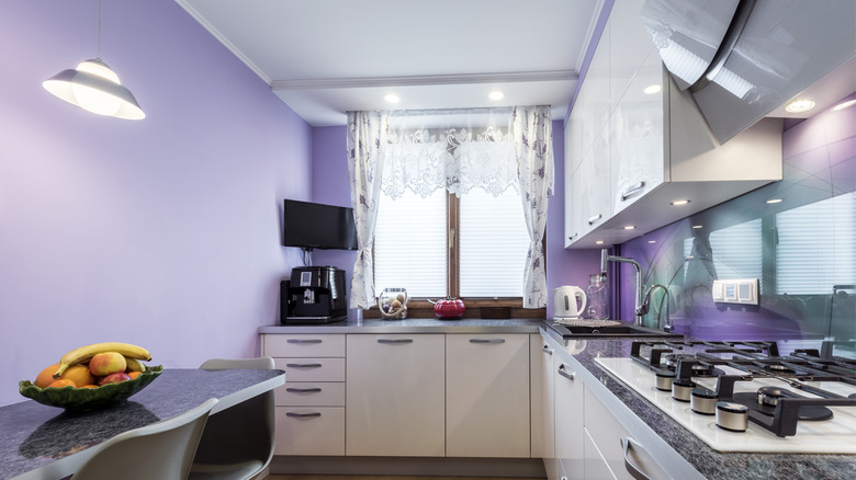 A small kitchen with purple painted walls.