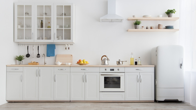 An all white modern kitchen with a black faucet.