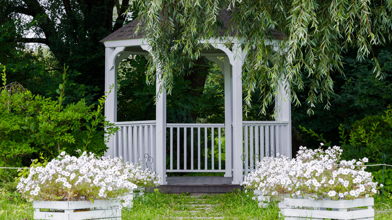 A white wooden gazebo with symmetrical flower boxes.